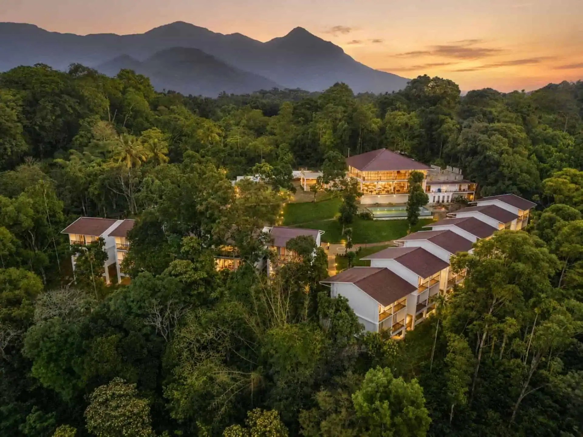 Aerial view of Vega Munnar Resorts at golden hour with layered mountain ridges